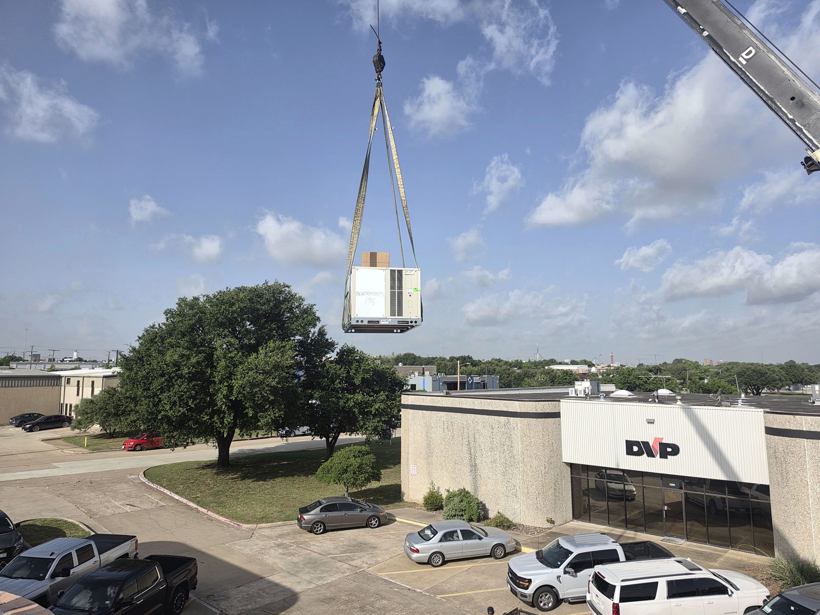 Crane lifting a new rooftop HVAC unit onto a commercial building during a Cyclone Heating & Air installation