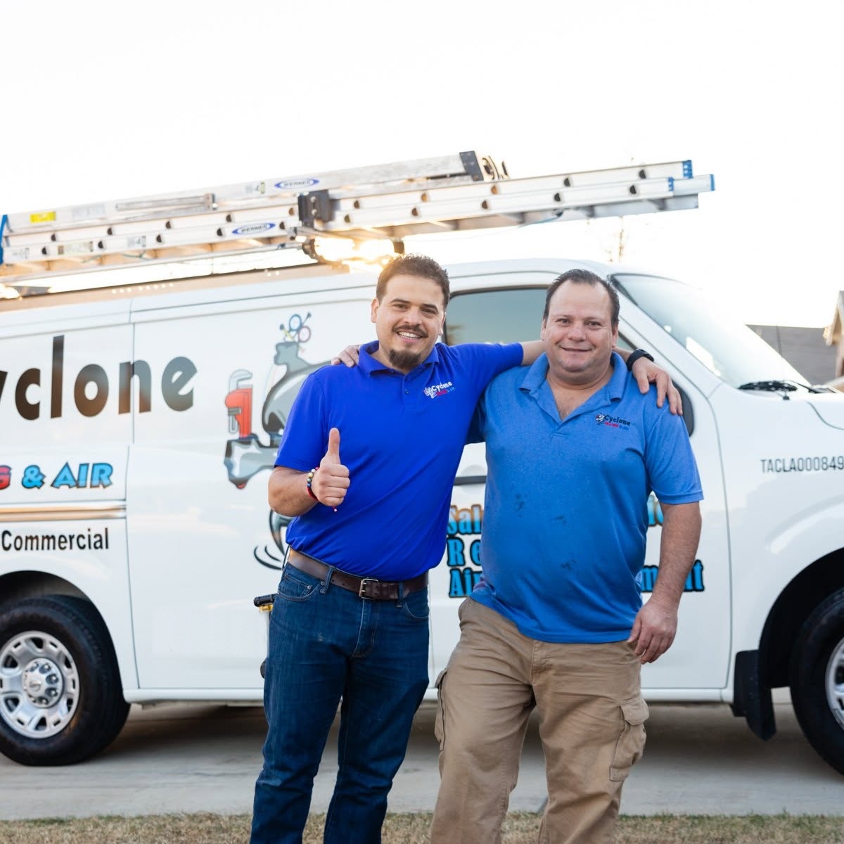 Two Cyclone Heating & Air crew members beside the branded service van