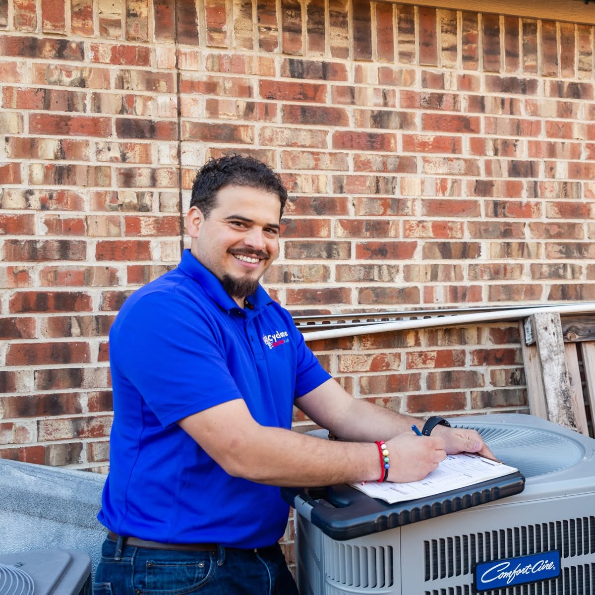 Mario, owner of Cyclone Heating & Air, writing up readings at a condenser