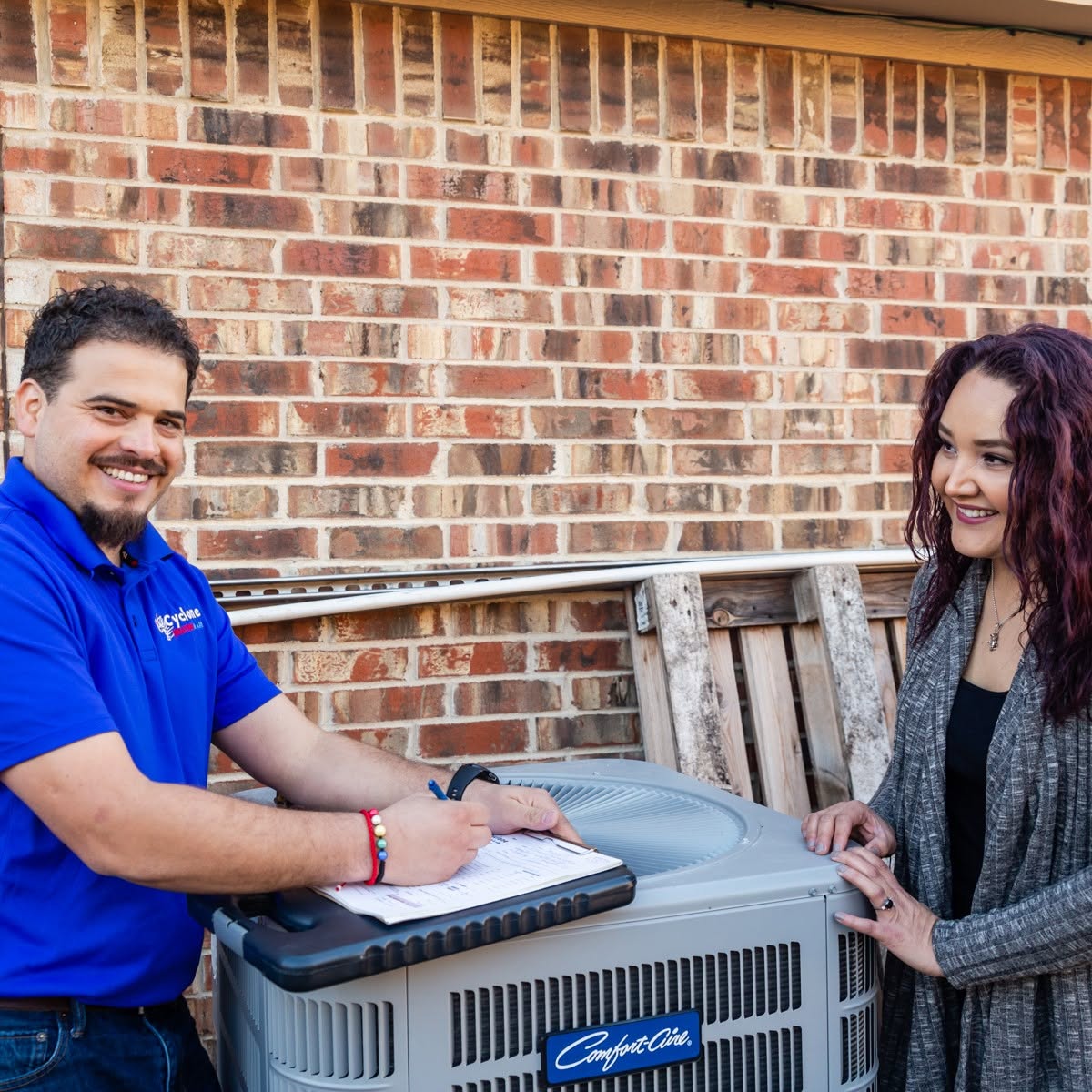 Mario, owner of Cyclone Heating & Air, reviewing an estimate with a customer at the outdoor AC condenser