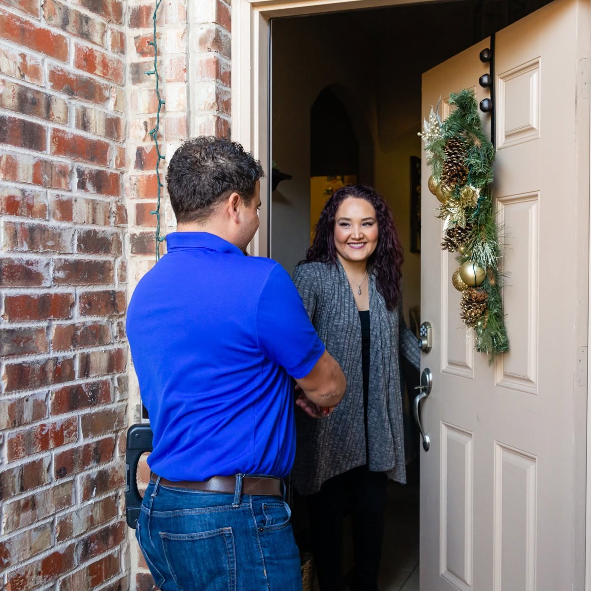 A Cyclone Heating & Air technician greeted by a customer at the front door