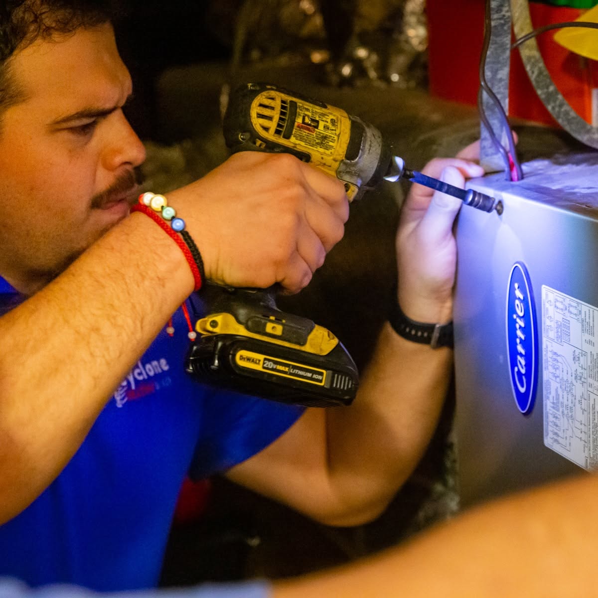 Cyclone HVAC technician making a repair inside a furnace cabinet at a Dallas home