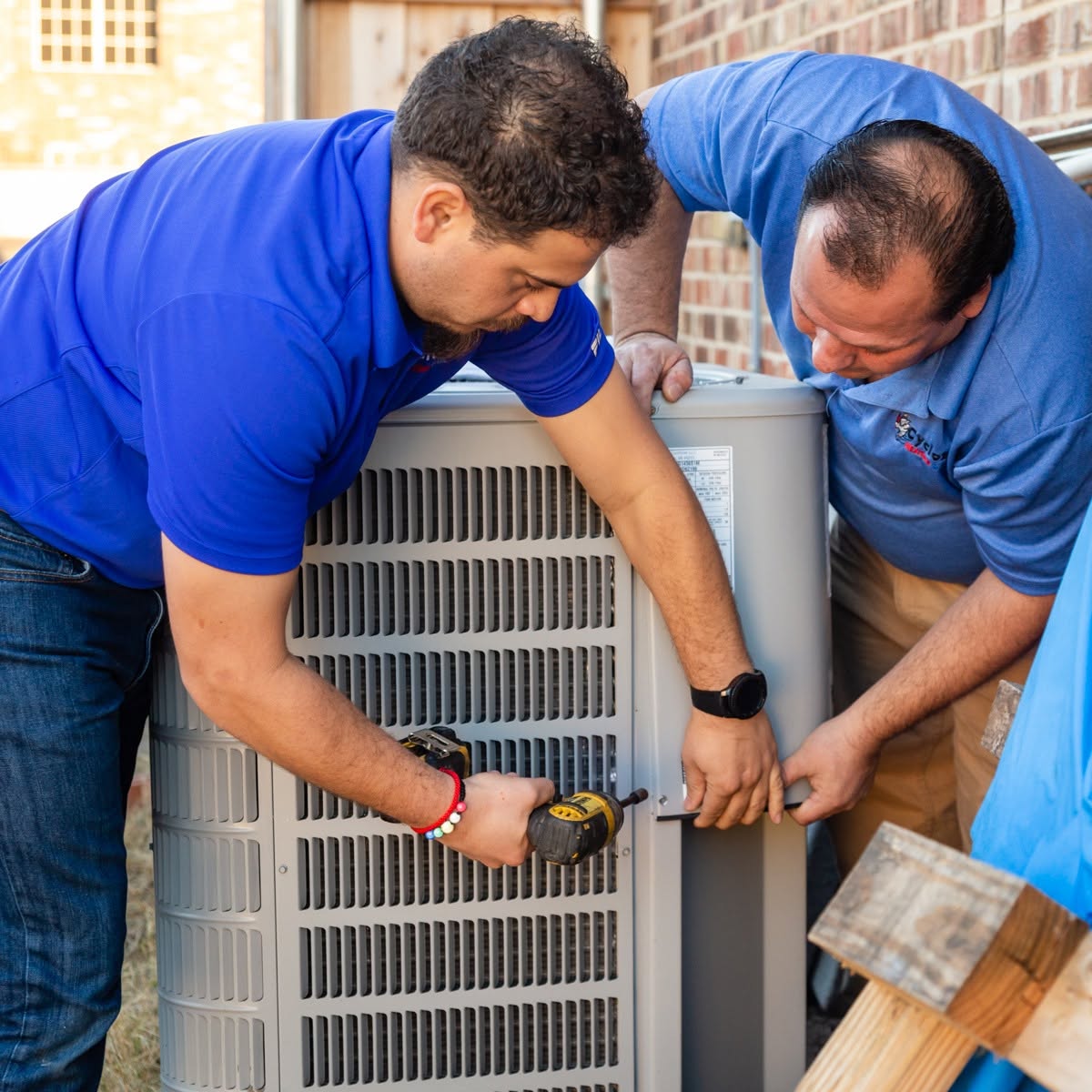 Two Cyclone technicians servicing an outdoor AC condenser